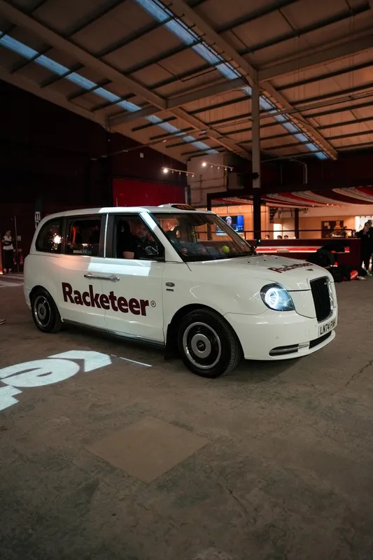 A white London taxi in Racketeer livery inside the venue.